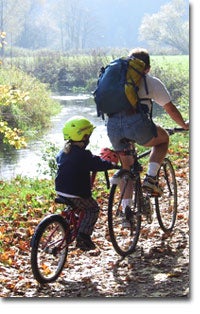Image of a father and son biking in the park.