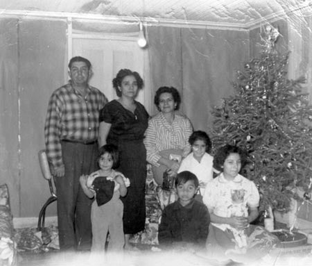 A family poses next to a Christmas tree in a black and white photo.