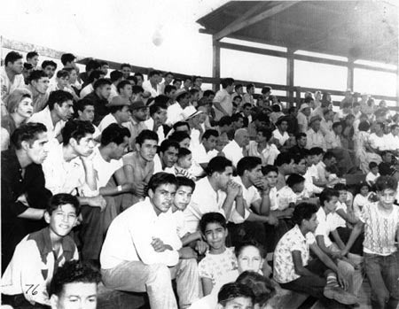 A black-and-white photo of a crowd of young people sitting on bleachers.