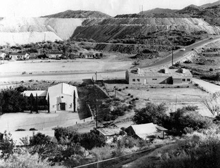 Black and white image of a small settlement near rocky, terraced hills.