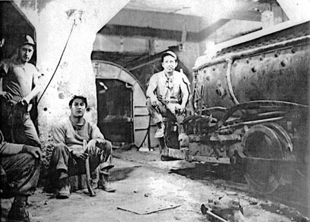 A black and white photo of miners with machinery underground.