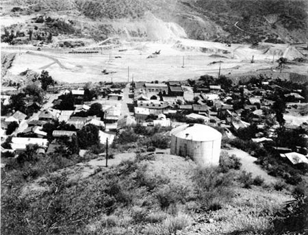 Aerial view of a small town with a large water tank and a mining area in the background.