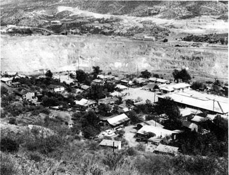 Aerial view of a small settlement next to a large open mine with surrounding hills.