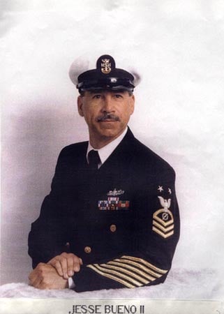Man in a naval uniform with insignias and a white cap.