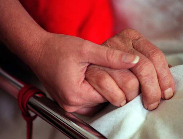 a family member holding hand of older family in hospital
