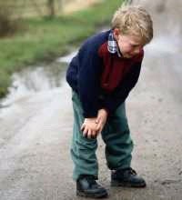 Young boy grabbing his knees in pain