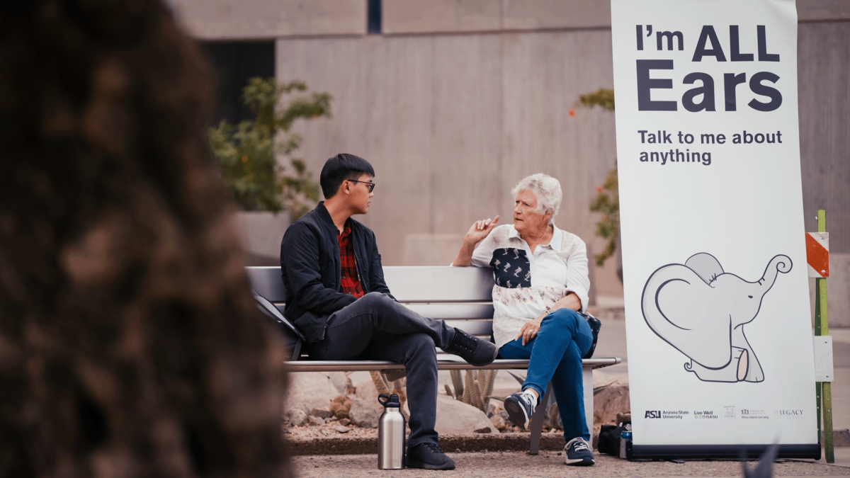 Older woman speaking to younger man on a bench.