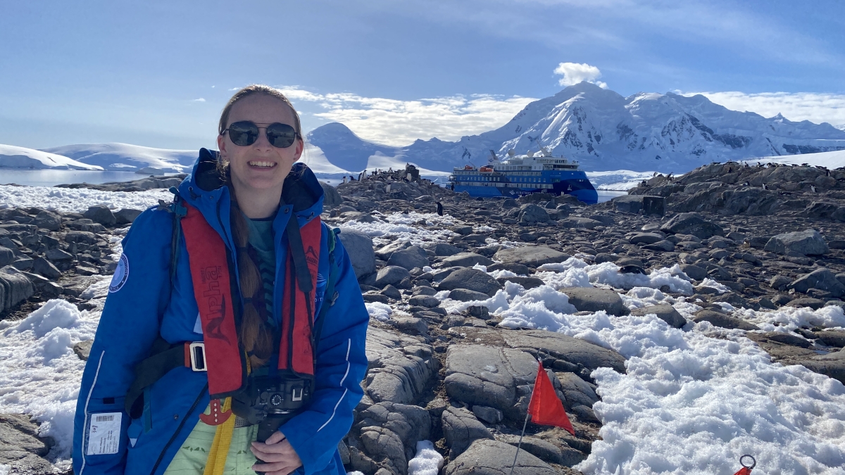 A woman poses in front of a glacier in Antarctica