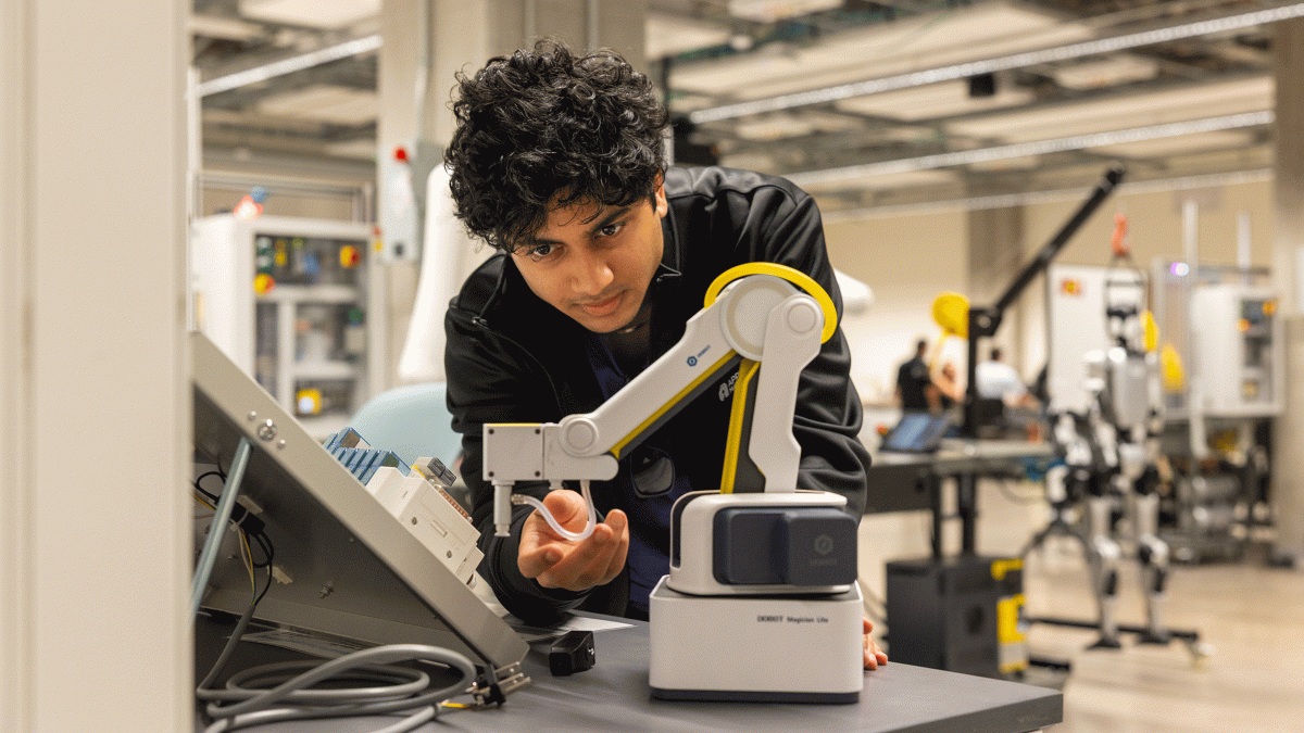 A college student works on a tabletop robotics arm