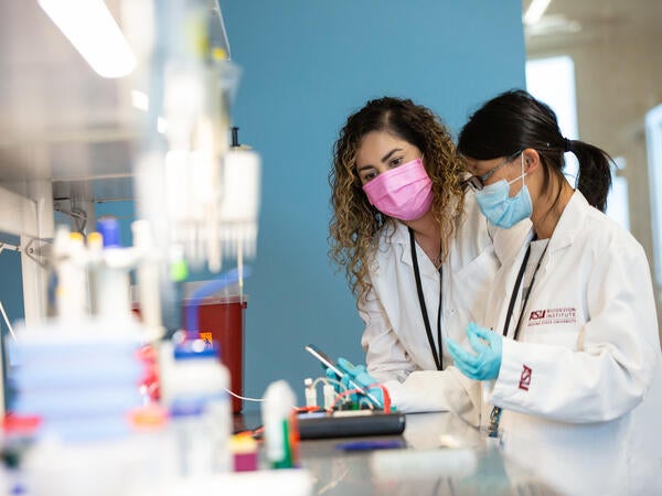 Two women working on an experiment with a phone in a medical lab
