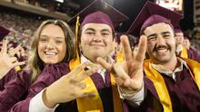Students in graduation regalia pose for a photo
